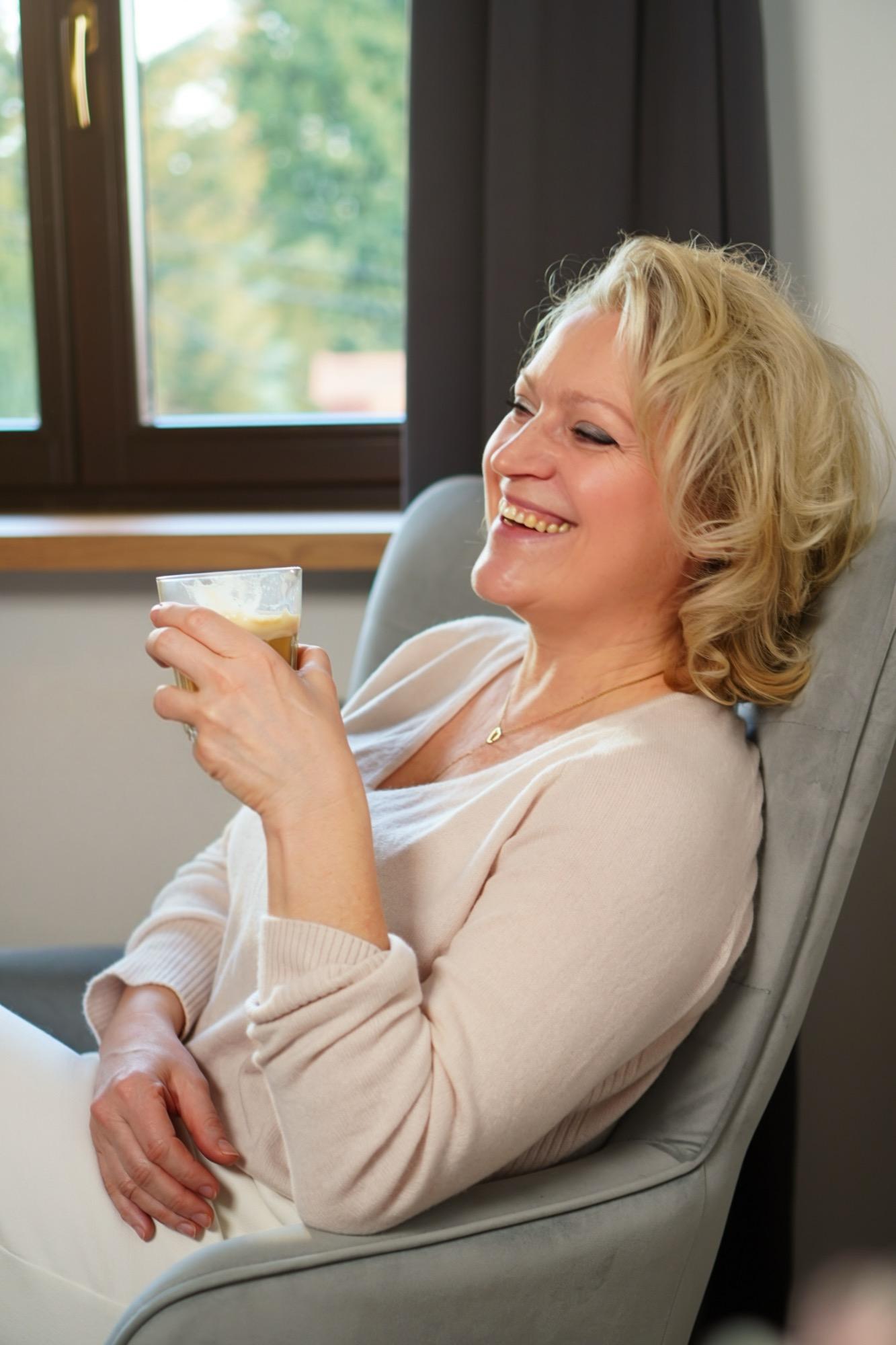 Joanna Macioł śmiejąca się w fotelu, prowadząca program grupowy W Harmonii dla kobiet